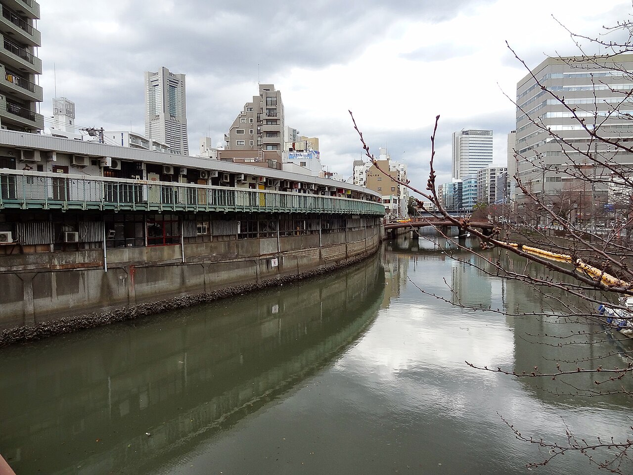 The rear of Fukutomicho's riverside buildings in Yokohama seen across the Ooka River, showing rows of air conditioner units stacked along the facade
